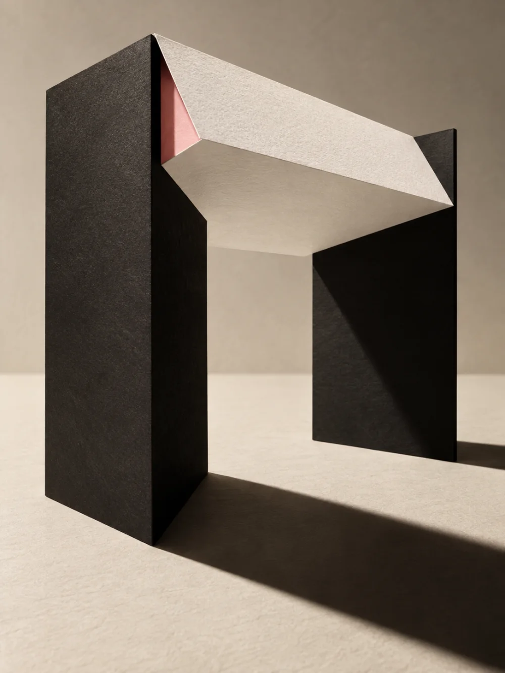 A black paper arch standing on a pale surface, casting a long shadow